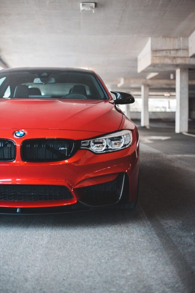 New luxury automobile with red rich color and strong bumper inside parking garage