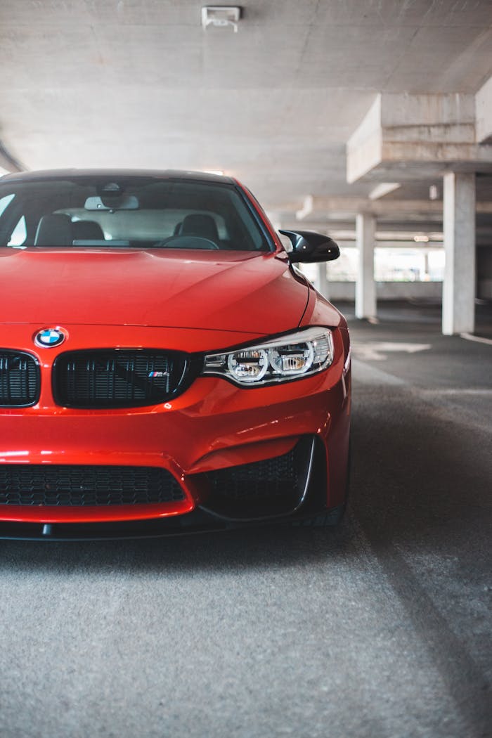 New luxury automobile with red rich color and strong bumper inside parking garage